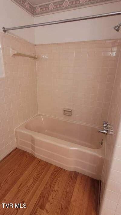 bathroom with hardwood / wood-style flooring and tiled shower / bath combo