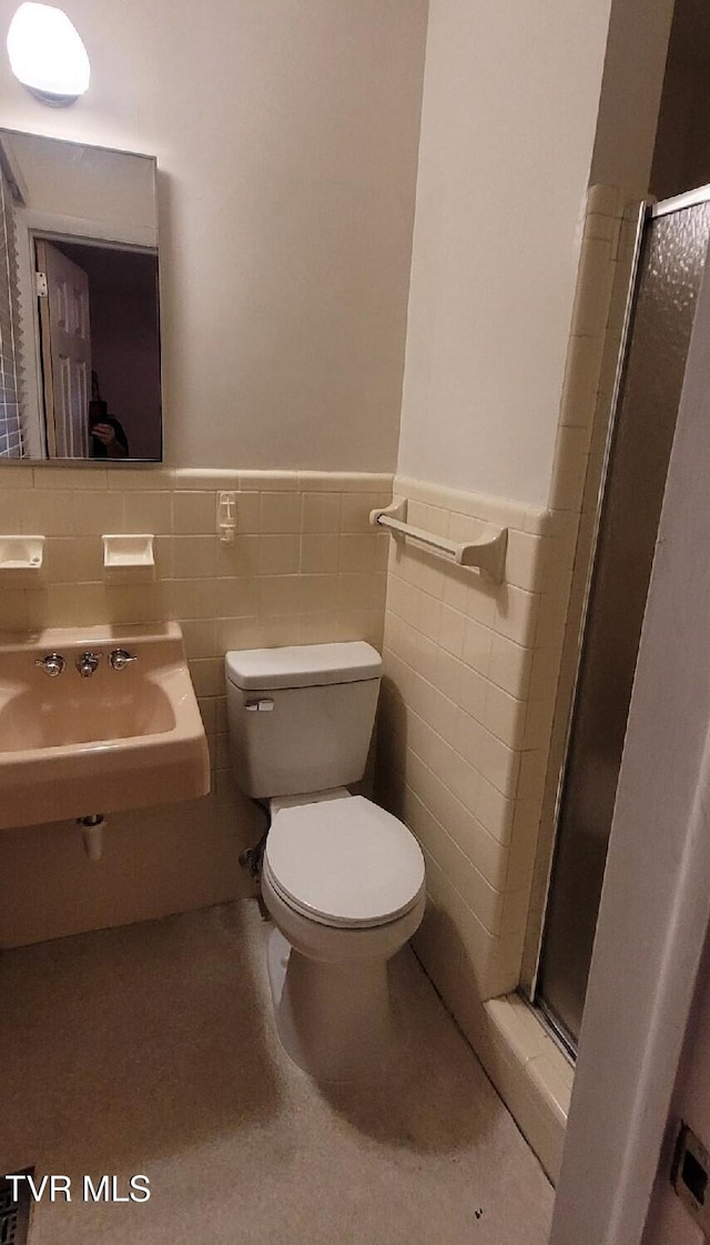 bathroom with sink, toilet, tile walls, and walk in shower