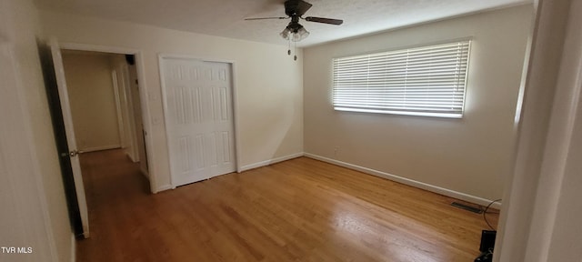 unfurnished bedroom featuring a closet, hardwood / wood-style flooring, and ceiling fan