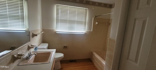 full bathroom featuring wood-type flooring, toilet, a healthy amount of sunlight, and sink