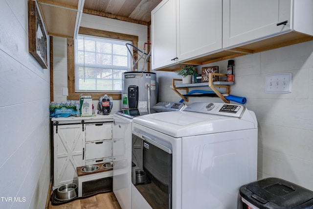 laundry area featuring cabinets, washing machine and dryer, light hardwood / wood-style floors, and water heater