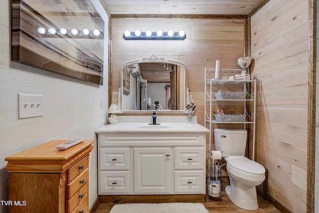 bathroom featuring hardwood / wood-style floors, vanity, toilet, and wooden walls