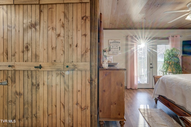 bedroom with access to outside, hardwood / wood-style flooring, wooden walls, and ceiling fan