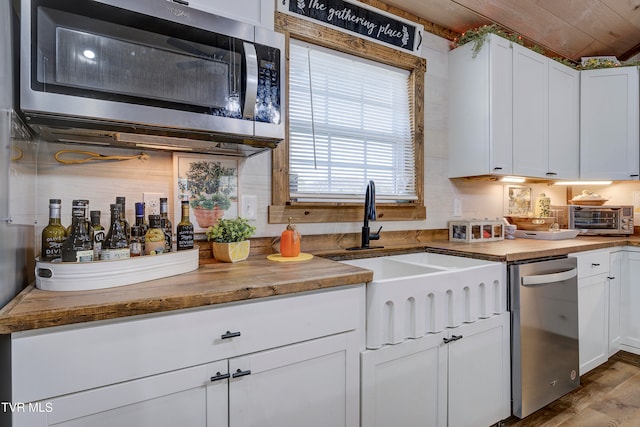 kitchen with white cabinets, appliances with stainless steel finishes, light wood-type flooring, and wood counters