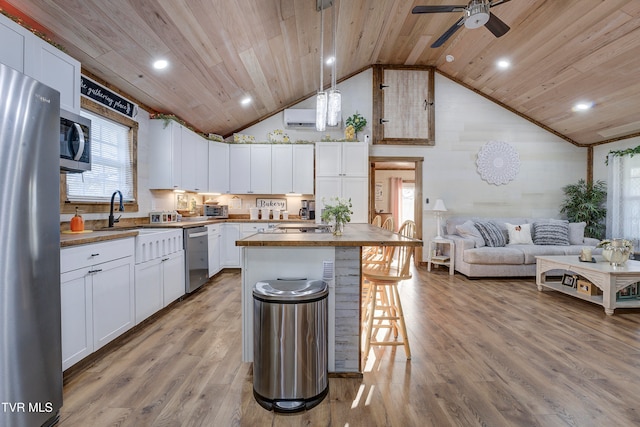 kitchen with hanging light fixtures, white cabinets, wood ceiling, and a kitchen island