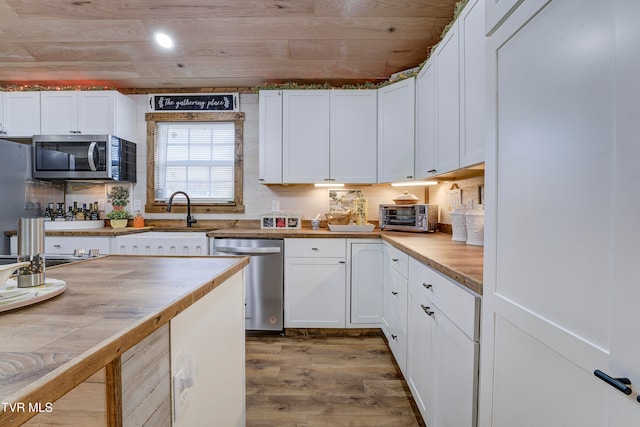 kitchen featuring white cabinets, sink, wood-type flooring, stainless steel appliances, and wood ceiling