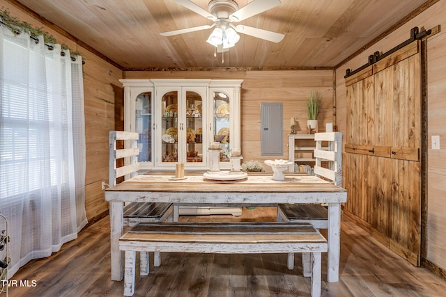 dining space featuring hardwood / wood-style floors, a barn door, and wood walls