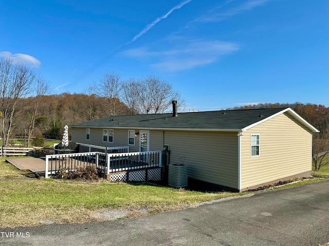 back of house with a lawn, a wooden deck, and central AC