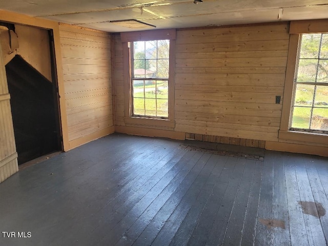 unfurnished room featuring dark hardwood / wood-style flooring and wooden walls