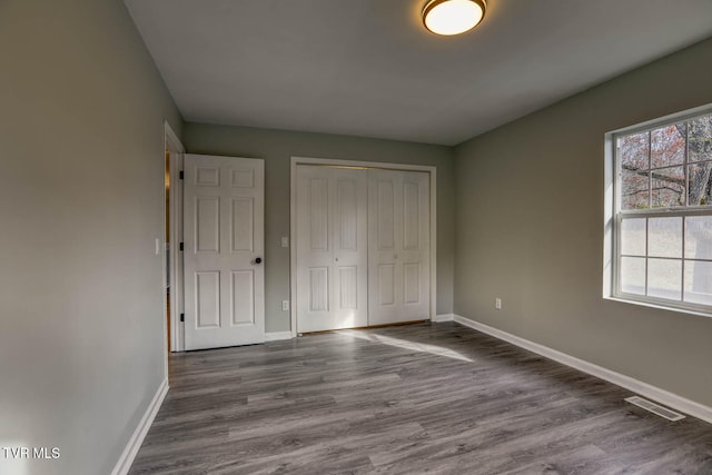 unfurnished bedroom with dark hardwood / wood-style floors and a closet