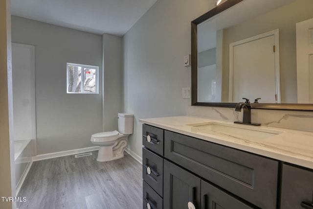 bathroom with a tub, toilet, vanity, and hardwood / wood-style flooring