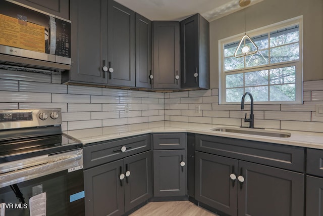 kitchen featuring backsplash, sink, light wood-type flooring, and appliances with stainless steel finishes