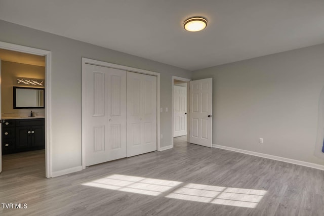 unfurnished bedroom with ensuite bathroom, light hardwood / wood-style floors, sink, and a closet