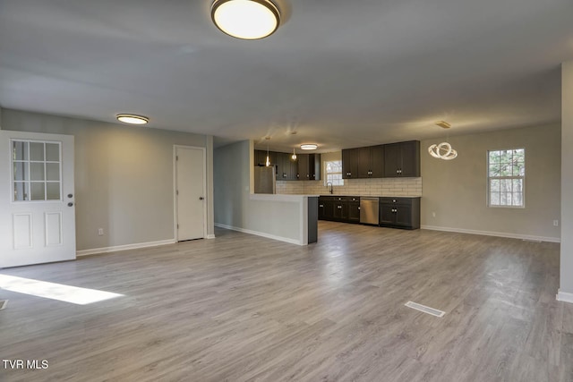 unfurnished living room featuring an inviting chandelier, light hardwood / wood-style flooring, and sink