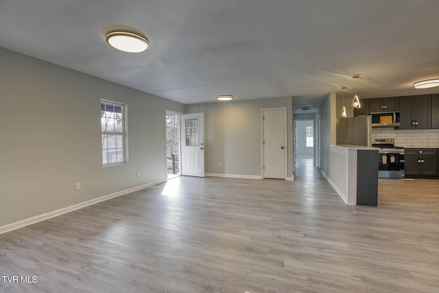 unfurnished living room featuring plenty of natural light and light wood-type flooring