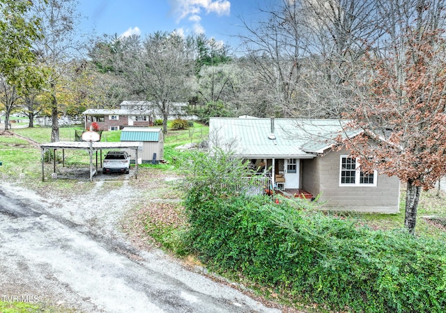 view of front facade featuring covered porch, a shed, and a carport