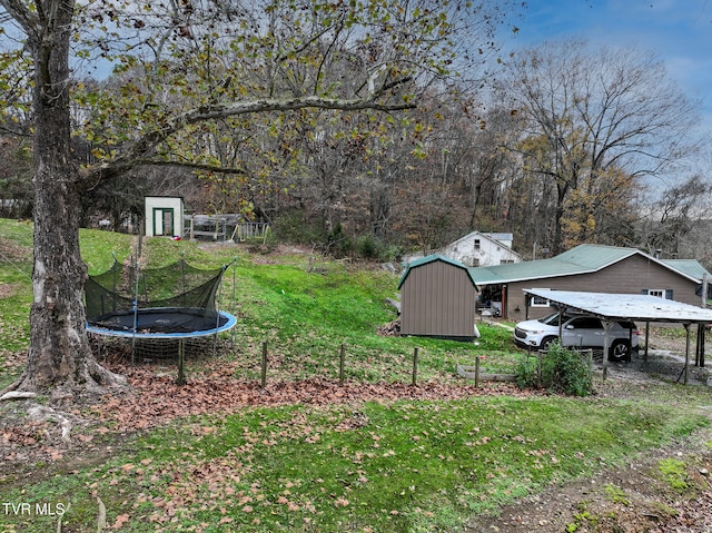 view of yard with a carport, a storage shed, and a trampoline