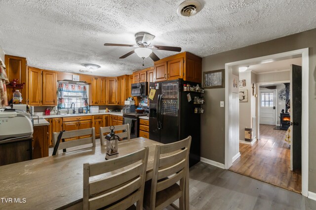 kitchen featuring a textured ceiling, stainless steel appliances, sink, hardwood / wood-style flooring, and a wood stove