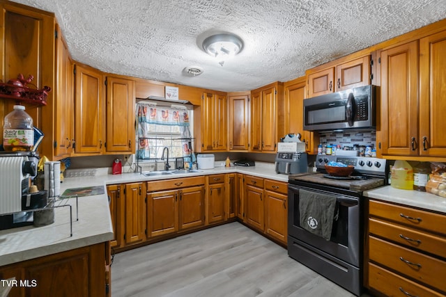 kitchen with a textured ceiling, light hardwood / wood-style floors, sink, and stainless steel appliances