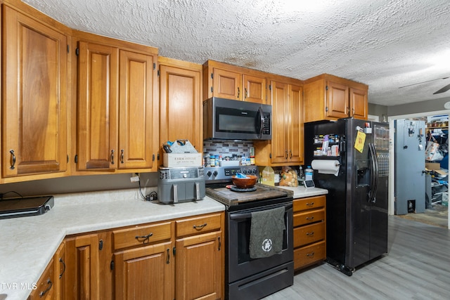 kitchen featuring decorative backsplash, a textured ceiling, ceiling fan, black appliances, and light hardwood / wood-style floors