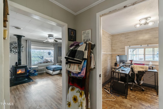 home office with hardwood / wood-style floors, ceiling fan, a wood stove, and a wealth of natural light