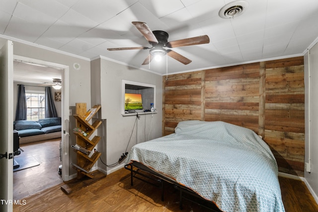 bedroom featuring hardwood / wood-style flooring, ceiling fan, and wood walls