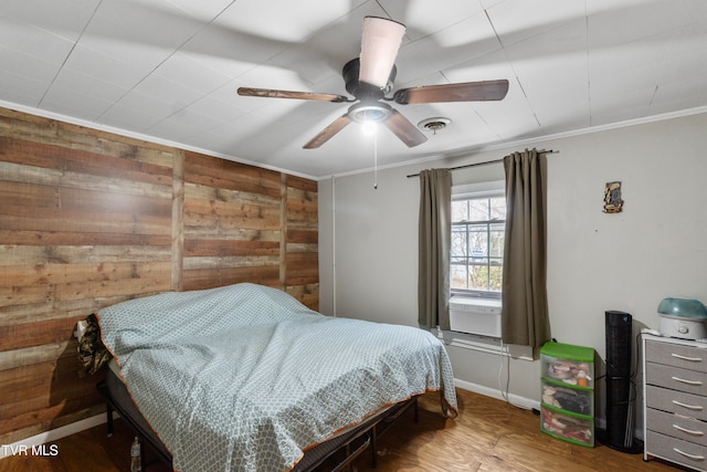 bedroom with hardwood / wood-style flooring, ceiling fan, crown molding, and wooden walls