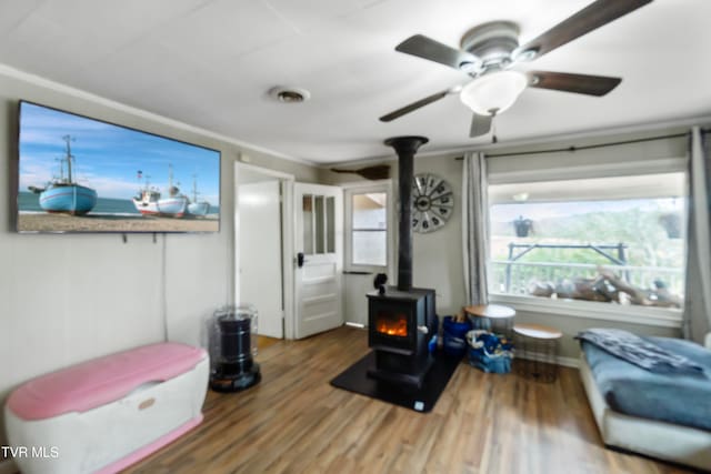 interior space with a wood stove, crown molding, and hardwood / wood-style floors