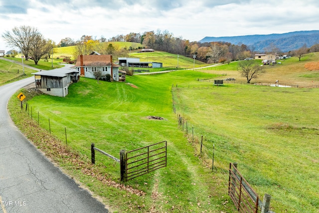 view of home's community with a mountain view, a rural view, an outdoor structure, and a yard