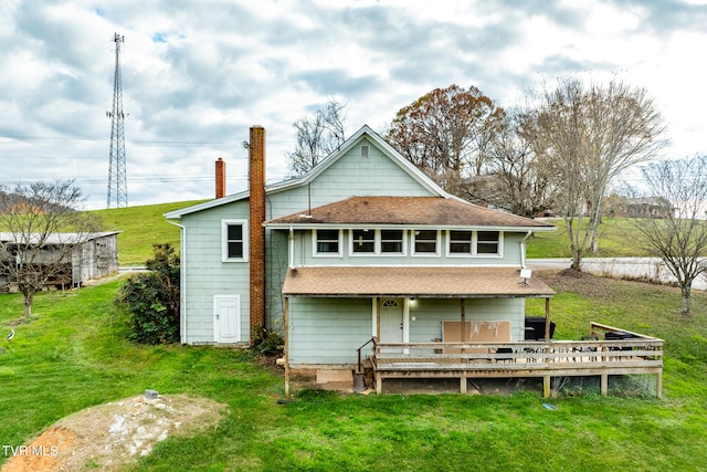 rear view of house featuring a lawn and a deck