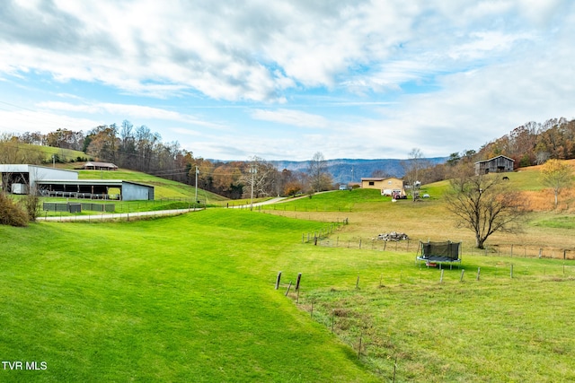 view of home's community featuring a trampoline, a rural view, and a lawn