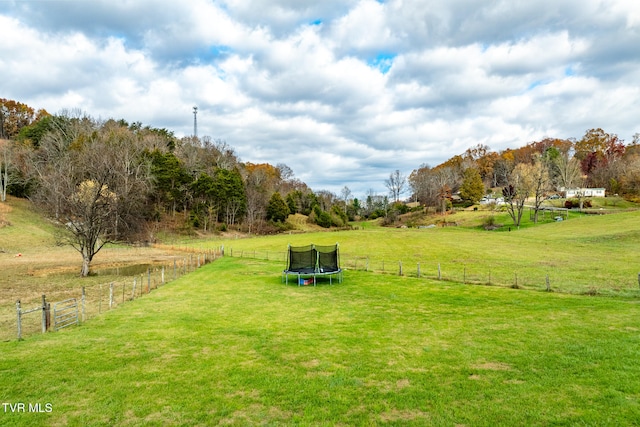 view of community featuring a rural view, a trampoline, and a lawn