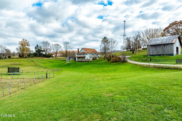 view of yard featuring a rural view, an outdoor structure, and a trampoline