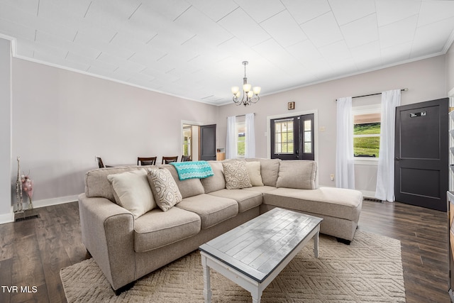 living room featuring an inviting chandelier, dark hardwood / wood-style floors, and ornamental molding