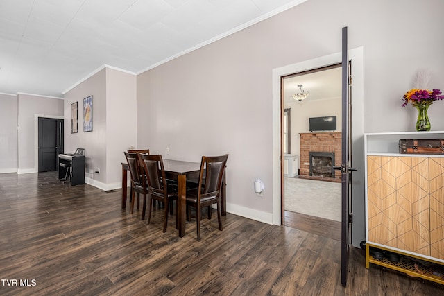 dining area with dark hardwood / wood-style floors, ornamental molding, and a brick fireplace