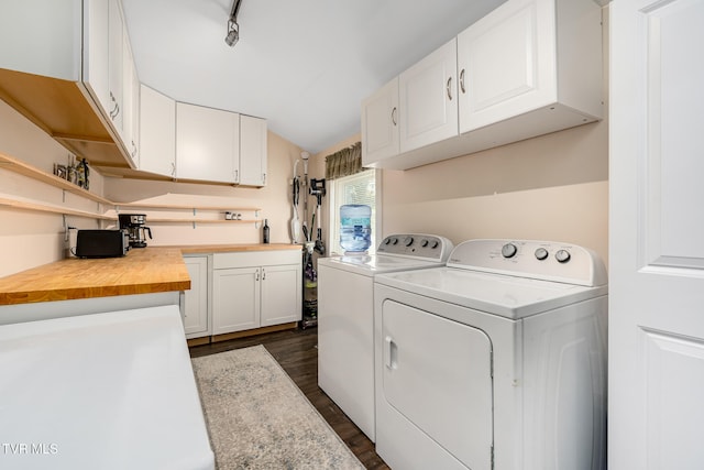 washroom featuring cabinets, dark hardwood / wood-style flooring, track lighting, and washing machine and clothes dryer