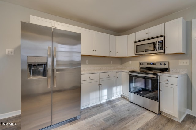 kitchen with white cabinets, appliances with stainless steel finishes, and light wood-type flooring