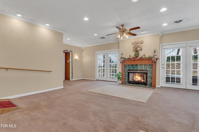 unfurnished living room with a tile fireplace, light colored carpet, ceiling fan, and crown molding