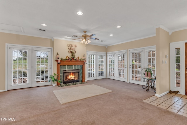 unfurnished living room featuring a fireplace, ceiling fan, light colored carpet, and crown molding