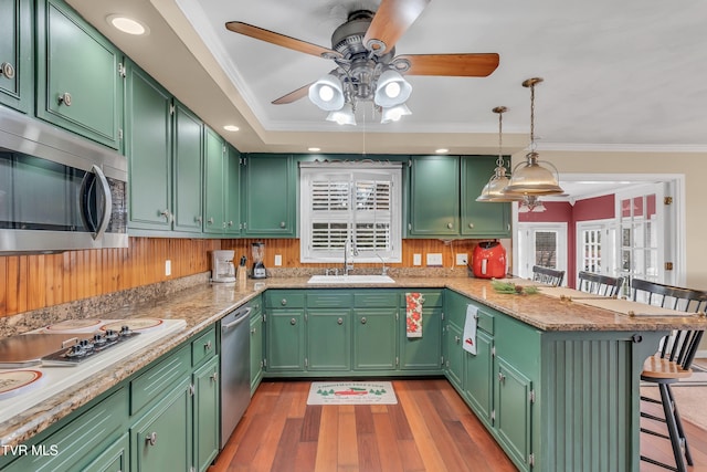 kitchen with kitchen peninsula, a breakfast bar, green cabinets, and sink