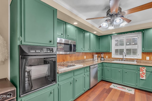 kitchen with stainless steel appliances, crown molding, sink, light hardwood / wood-style flooring, and green cabinetry