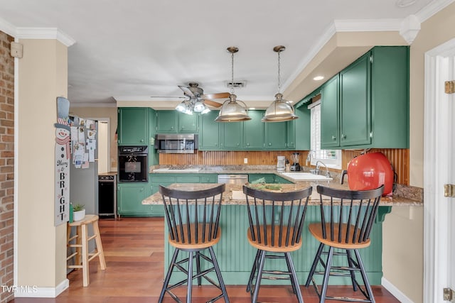 kitchen with a breakfast bar, green cabinetry, dark hardwood / wood-style floors, kitchen peninsula, and stainless steel appliances