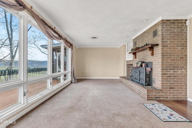 unfurnished living room featuring carpet, a wood stove, and crown molding