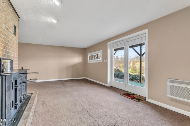 unfurnished living room with dark carpet, a textured ceiling, a wood stove, and a wall unit AC