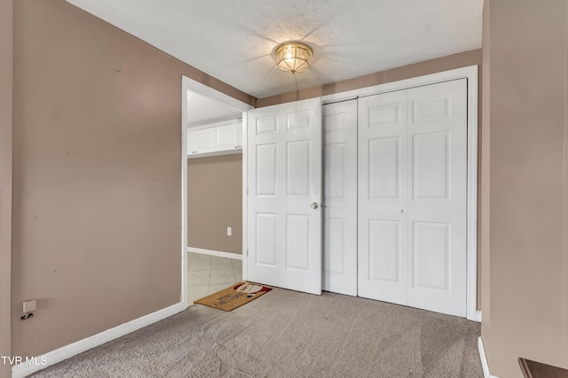 unfurnished bedroom with carpet flooring, a textured ceiling, and a closet