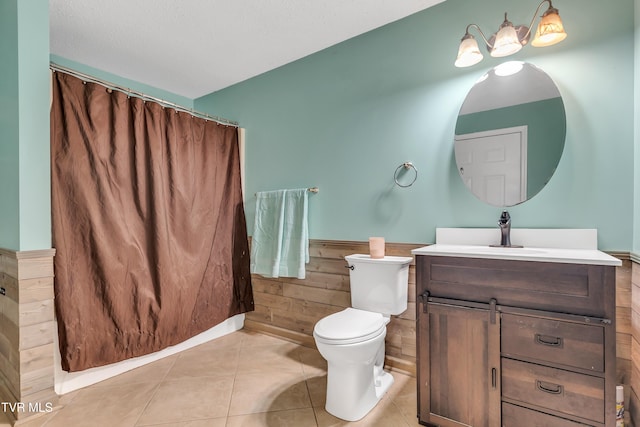 bathroom featuring vanity, tile patterned floors, wooden walls, toilet, and a textured ceiling