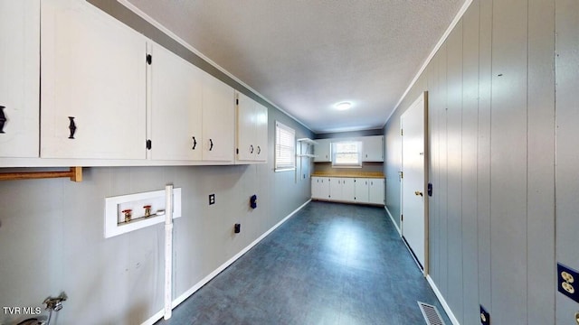 laundry room with cabinets, hookup for a washing machine, a textured ceiling, crown molding, and wooden walls