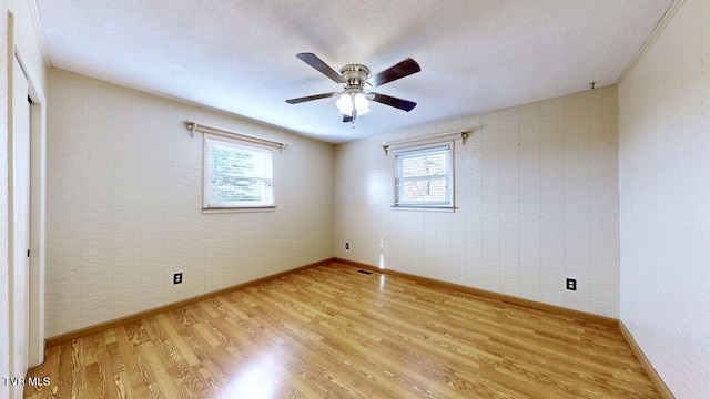 empty room featuring ceiling fan, plenty of natural light, light hardwood / wood-style floors, and a textured ceiling