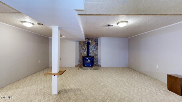 basement with carpet floors, a wood stove, and ornamental molding