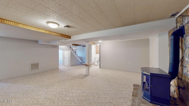 basement with carpet flooring and a wood stove